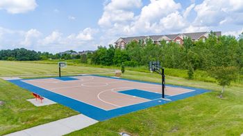 a basketball court in a park with houses in the background